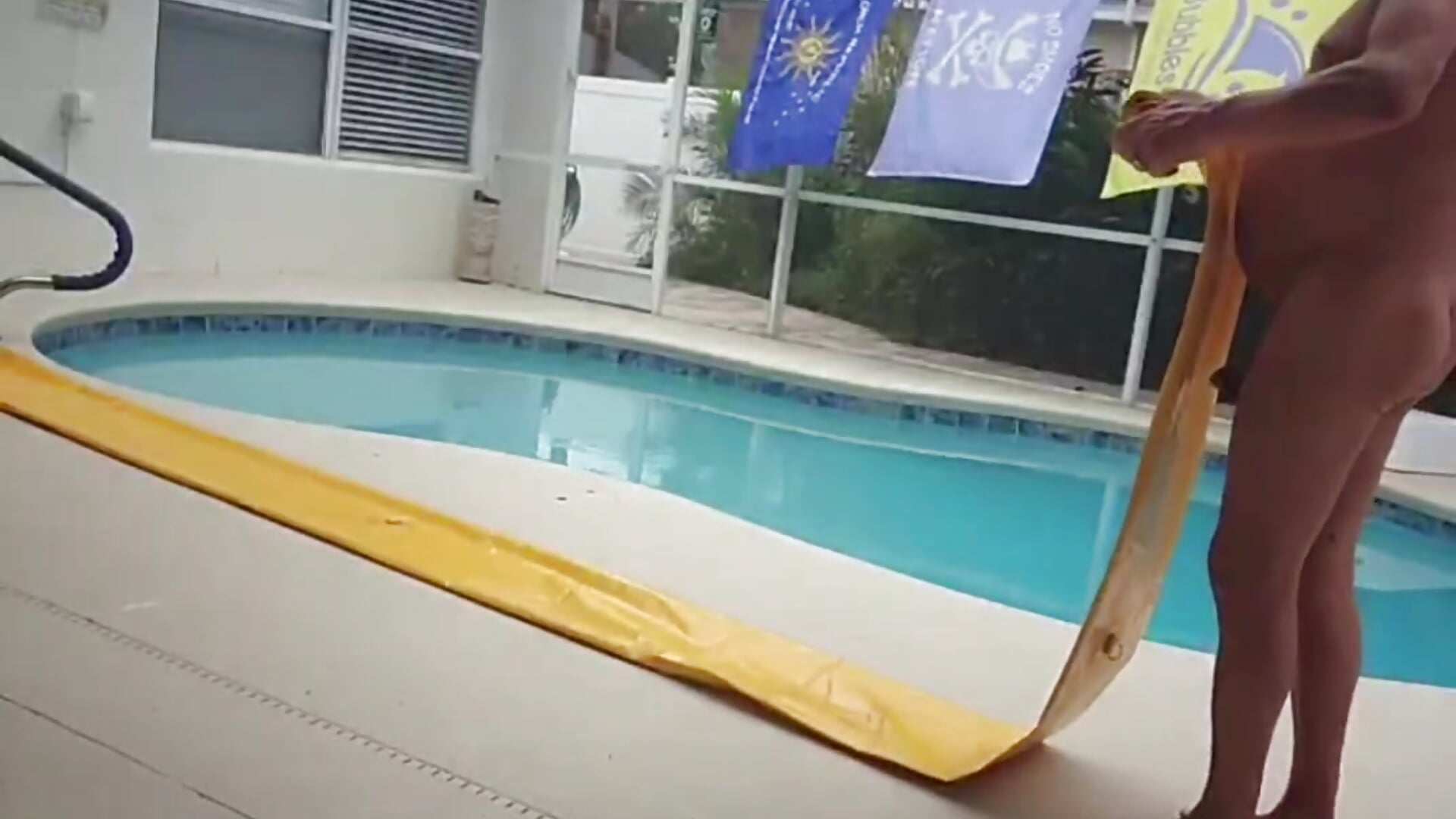 Naked by my pool rolling up a big water tube.