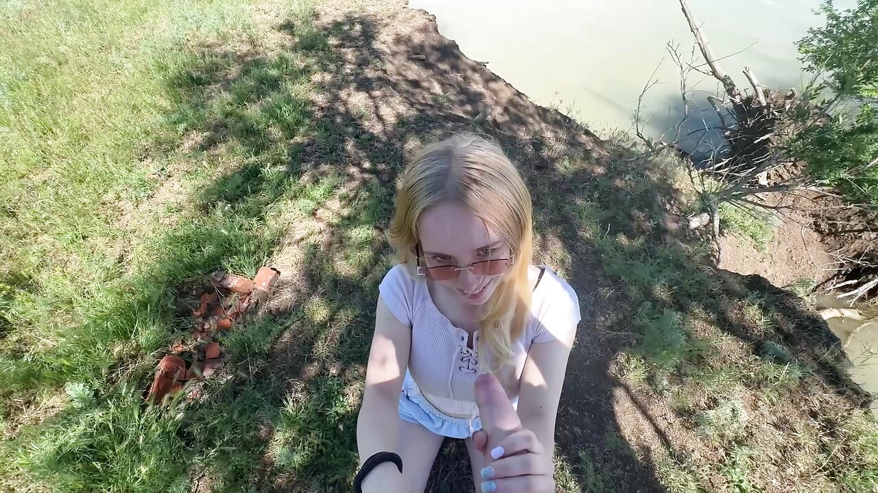 Emily jerks off Sam's cock by the lake.